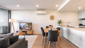 Una sala de estar moderna con televisor, sofá y comedor.