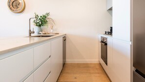 Eine Küche mit weißen Schränken, einem Edelstahlkühlschrank und Holzboden.