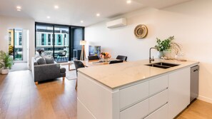 Een moderne keuken met een centraal eiland, een eethoek met tafel en stoelen, en een woonkamer met een bank en salontafel.