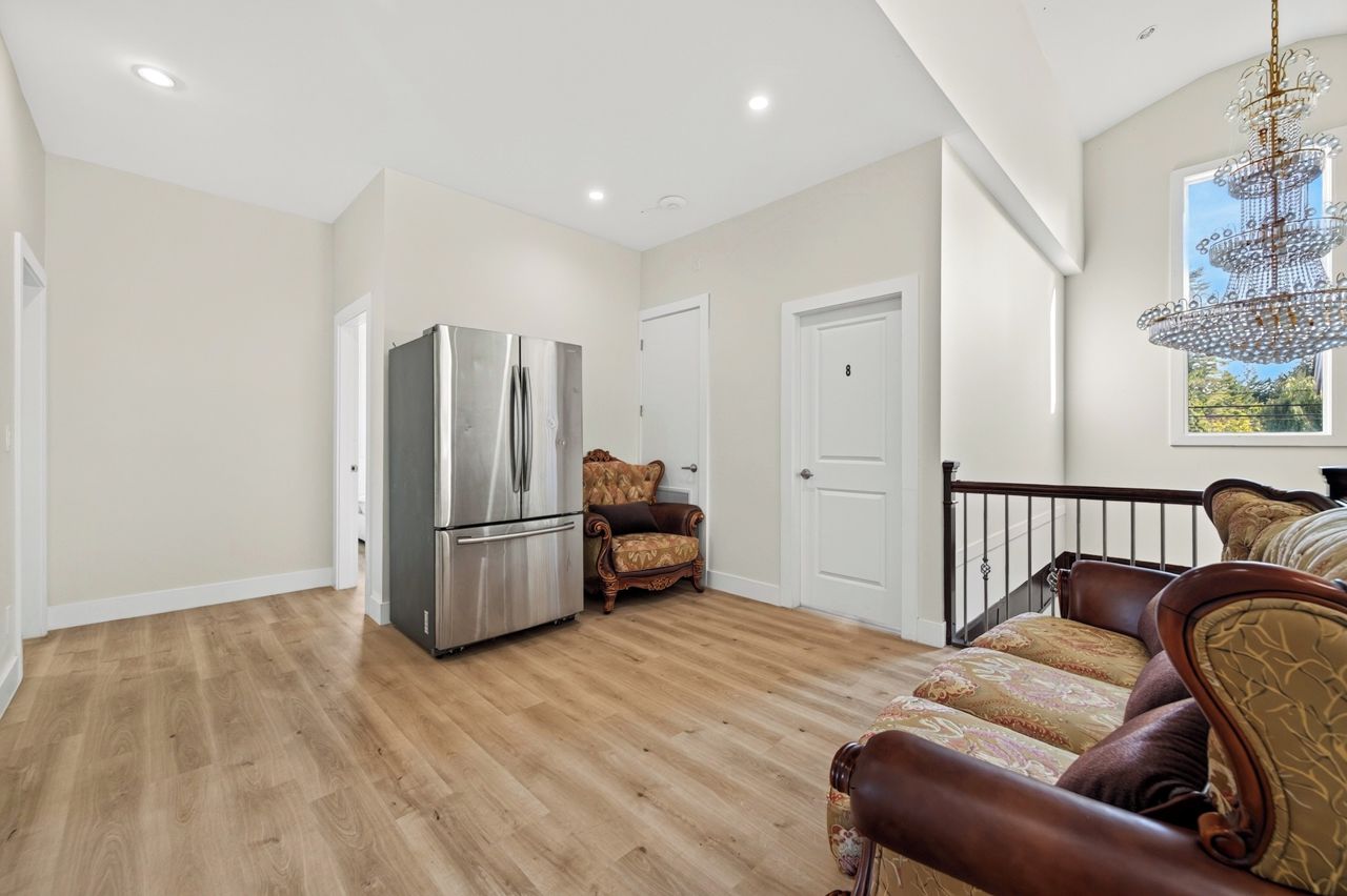A spacious living area with a modern kitchen, a chandelier, and a staircase leading to another level.