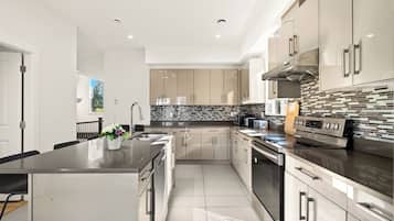 Una cocina moderna con una isla central, electrodomésticos de acero inoxidable y salpicadero de azulejos.