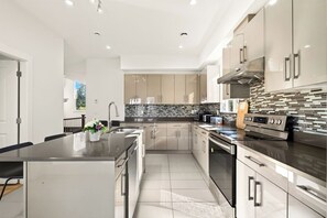 A modern kitchen with a central island, stainless steel appliances, and a tiled backsplash.