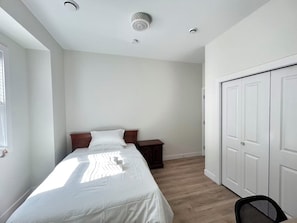 A bedroom with a bed, a nightstand, a wardrobe, and a window. - Surrey City Centre Ensuite near Skytrain (Surrey)
