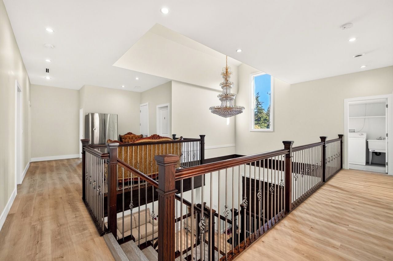 A spacious interior with a wooden staircase, a chandelier, and a view of the outdoors.