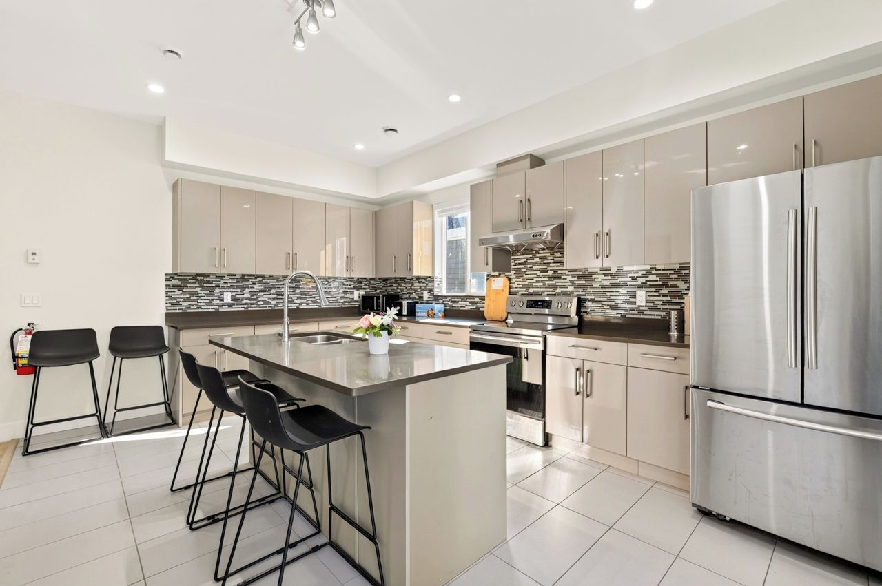 A modern kitchen with a central island, stainless steel appliances, and bar stools.