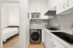 Cocina pequeña equipada con lavadora, microondas y lavabo.
