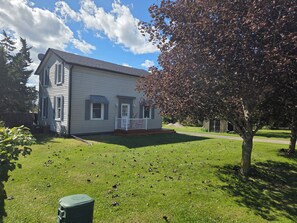 A two-story house with a front porch, a lawn, and a tree. - Stay Cozy Orchard (Clarington)