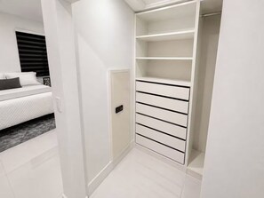 Un dressing avec des étagères blanches et une porte.