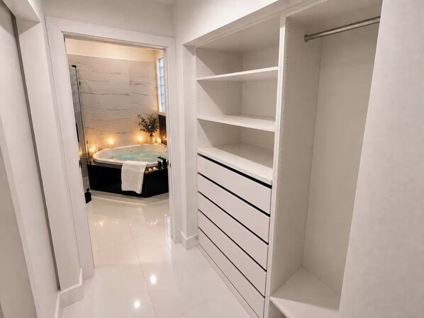A modern bathroom with a bathtub, a vanity with drawers, and a walk-in closet with shelves. - Lakefront Pool Home near Wellington Polo & Beaches (West Palm Beach)
