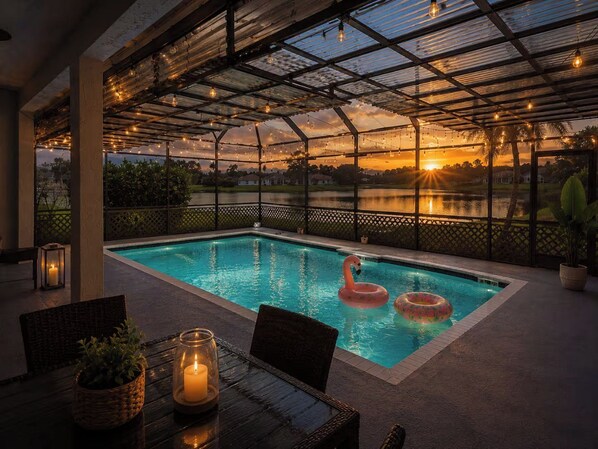 A swimming pool with a glass ceiling, surrounded by chairs and a table with candles. - Lakefront Pool Home near Wellington Polo & Beaches (West Palm Beach)