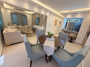 A modern living room with a sofa, a coffee table, and a dining area with chairs and a table. - MOONLIGHT APARTMENT NEAR THE BEACH (Puerto Plata)
