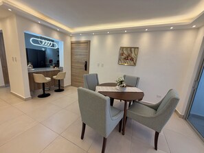 A modern dining area with a round table, four grey chairs, and a decorative vase. - MOONLIGHT APARTMENT NEAR THE BEACH (Puerto Plata)