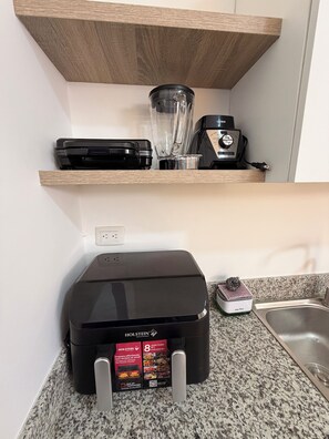 Eine Küche mit einer Arbeitsplatte, einer Kaffeemaschine, einem Mixer und einem Staubsauger.