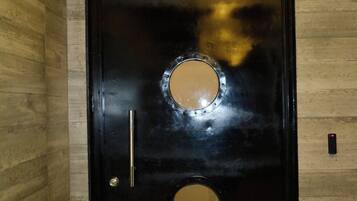 Una puerta negra con la palabra 'RUELLE' encima, una ventana redonda y una cerradura.
