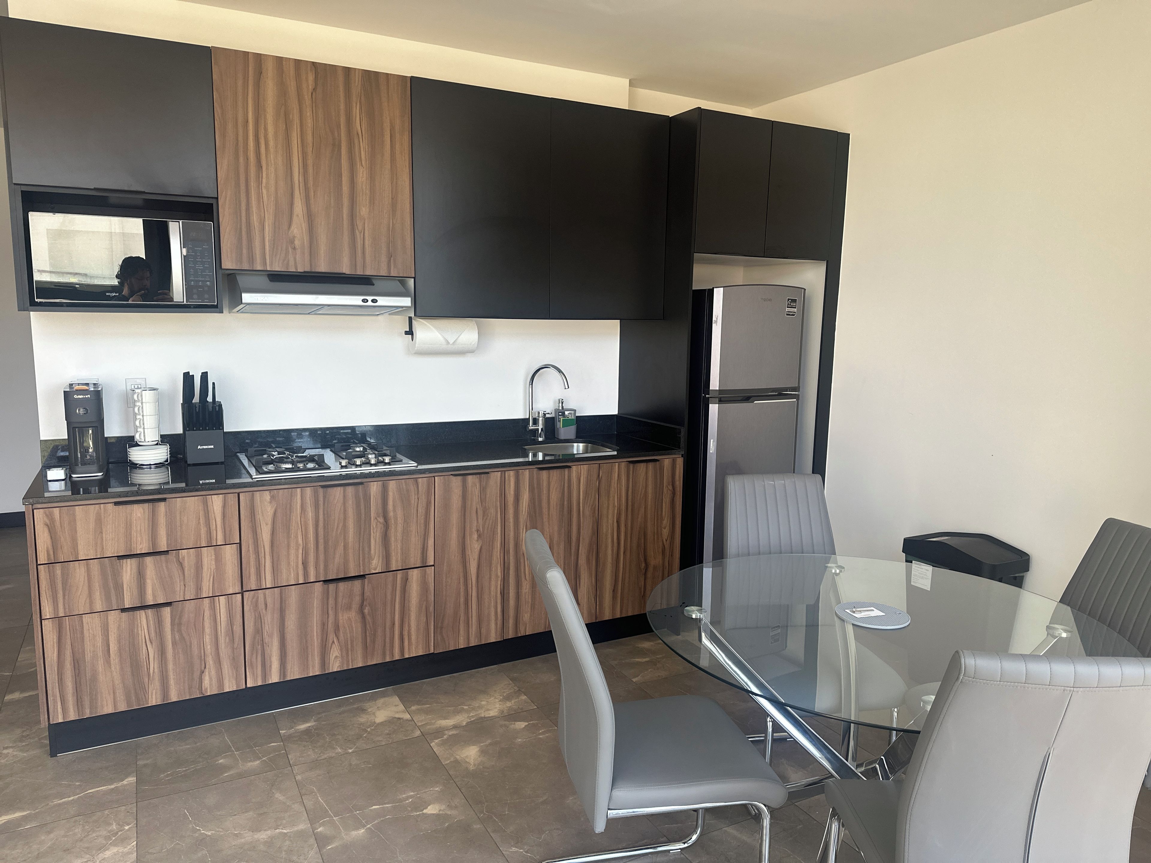 A modern kitchen with a built-in stove, microwave, and stainless steel refrigerator.