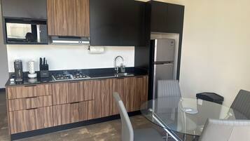 A modern kitchen with a built-in stove, microwave, and stainless steel refrigerator.