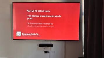 A flat-screen TV mounted on a wall displaying a red screen with text and a logo.