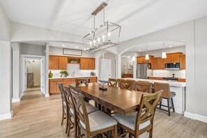 Eine geräumige Küche mit Holzschränken, einem Edelstahlkühlschrank und einem Essbereich mit einem großen Holztisch und Stühlen.