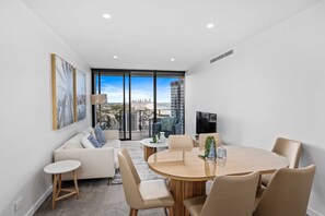 A modern living room with a sofa, coffee table, and dining table. - Luxurious Beachfront Retreat in Burleigh Heads (Gold Coast)