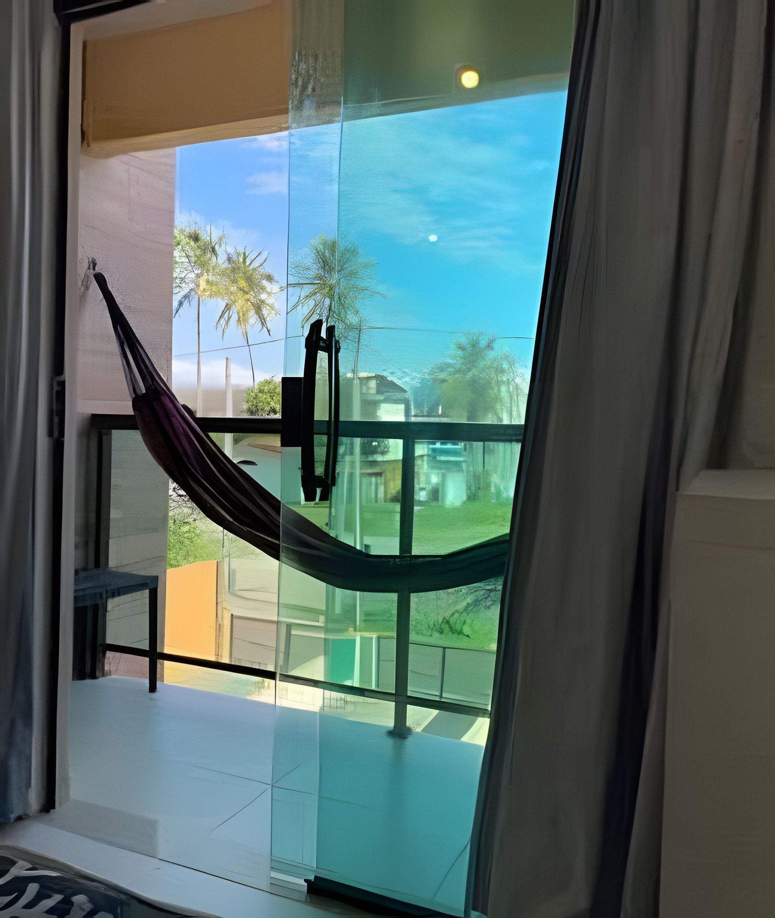 Una habitación con una puerta de vidrio que da a un balcón con una hamaca.
