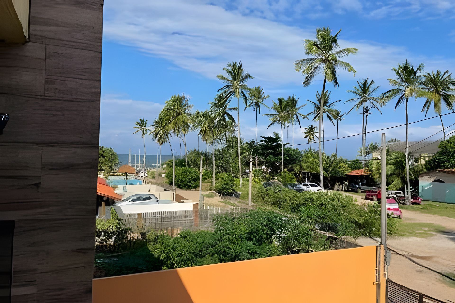 Vista de uma área residencial com palmeiras altas, piscina e céu azul límpido.