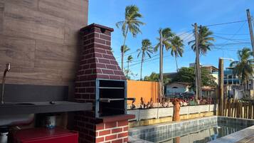 A brick-built outdoor oven adjacent to a swimming pool, with a red cabinet and a water feature nearby.
