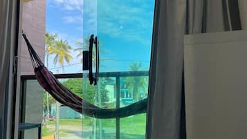 Ein Zimmer mit einer großen Schiebetür, die auf einen Balkon mit einer Hängematte und Palmen führt.