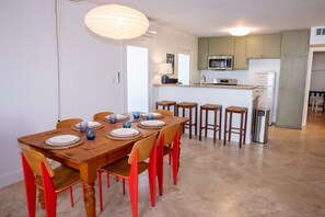 A dining area with a wooden table set for six, surrounded by red chairs. - Steps to the Sand: Mid-Century 2BR with Ocean-View Patio by Venice Pier (Marina del Rey)