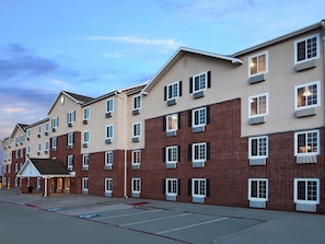 A multi-story hotel with a parking lot in front. - Room in McKinney (McKinney)