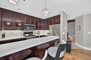 A modern kitchen with dark wood cabinets, stainless steel appliances, and a white countertop.