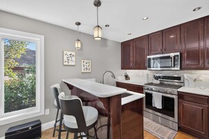 Una cocina moderna con una isla central, electrodomésticos de acero inoxidable y armarios de madera oscura.
