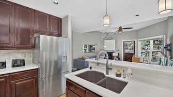 A modern kitchen with a stainless steel refrigerator, double sink, and wooden cabinets.