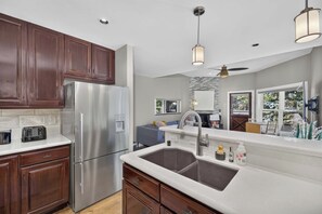 A modern kitchen with a stainless steel refrigerator, double sink, and wooden cabinets.