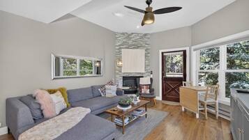 A living room with a fireplace, a sofa, a coffee table, and a dining area with chairs.