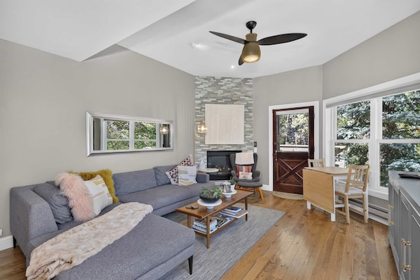 A living room with a fireplace, a sofa, a coffee table, and a dining area with chairs.