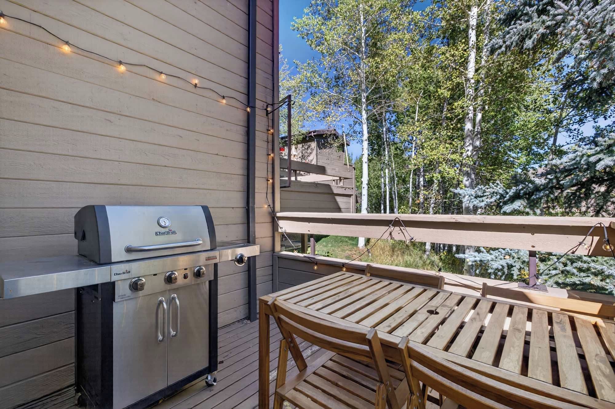 Une terrasse extérieure équipée d’un barbecue intégré, d’une table en bois et de chaises.