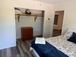 Un dormitorio con cama, cómoda, armario con espacio para colgar y suelo de madera.
