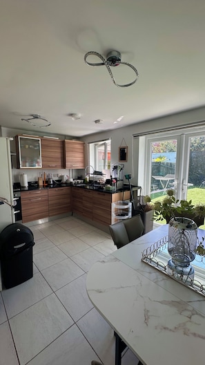 A modern kitchen with a central island, built-in appliances, and a dining area with a view of the garden.