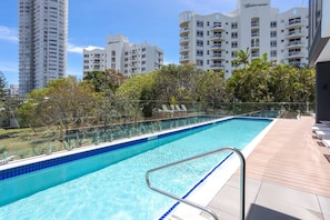 A swimming pool with a metal railing, surrounded by a wooden deck and lush greenery. - 2 Bedroom Luxury in Burleigh Heads! (Gold Coast)