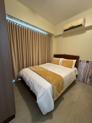 Ein Hotelzimmer mit einem Bett, Vorhängen, einer Klimaanlage und einem Fliesenboden.