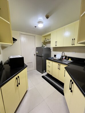 Una cocina compacta con refrigerador, estufa, pileta y placares.