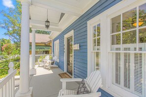 A porch with white railings, a bench, and two Adirondack chairs. - The Hamilton a Stylish Downtown Bungalow (High Point)