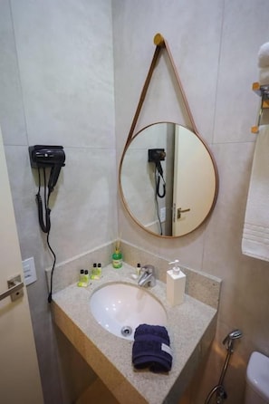 A bathroom with a sink, mirror, towel rack, and a hairdryer. - Pousada Thermas das Montanhas (Aguas de Lindoia)