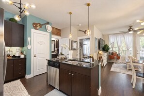 A modern kitchen with a central island, dark cabinetry, and pendant lighting. - The Bentley Collection - The Blue Ivy (Dallas)