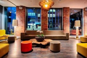 Eine moderne Lounge-Ecke mit einer Sofagarnitur, einem Couchtisch mit Pflanze und einem roten Pouf.