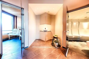 En modern hotellobby med en sittgrupp, ett litet bord med en skål med frukt och en krukväxt.