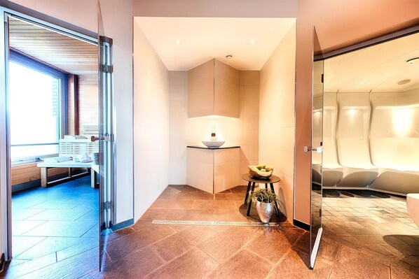 Eine moderne Hotellobby mit einer Sitzecke, einem kleinen Tisch mit Obstschale und einer Topfpflanze.