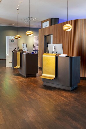 Et receptionsområde med to diske, hver med en computer og en telefon. Der hænger lysekroner over disken.