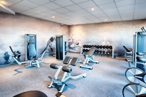 Et fitnesscenter med træningsmaskiner, håndvægte og et vægmonteret stativ til håndvægte.
