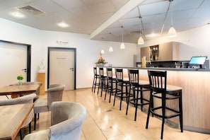 Ein Restaurant mit Barbereich, verschiedenen Sitzgelegenheiten und einem modernen, sauberen Interieur.